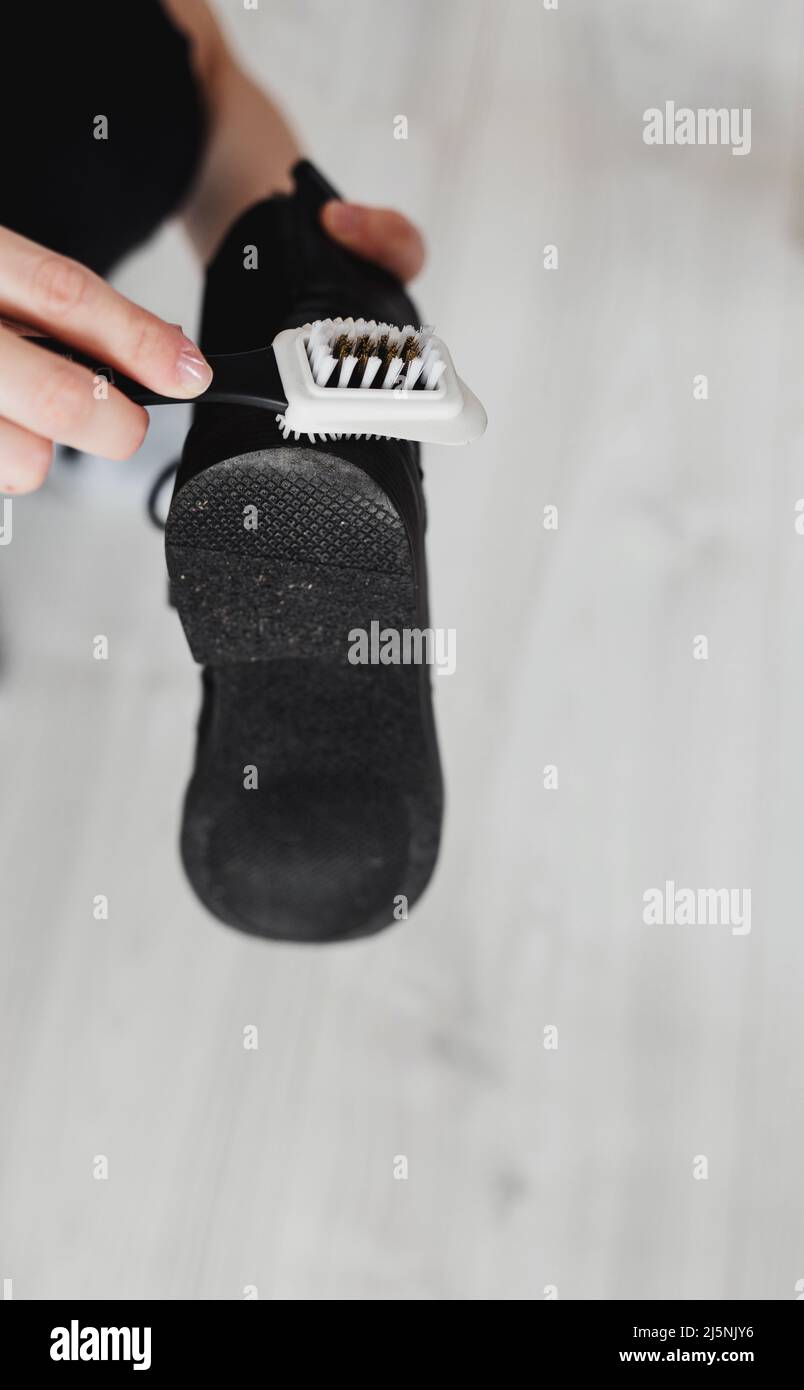 le mani strofinano il bagagliaio in pelle nera dalla polvere di sporco. Cura per pelle shoes. Protezione di scarpe in piovoso, Foto Stock