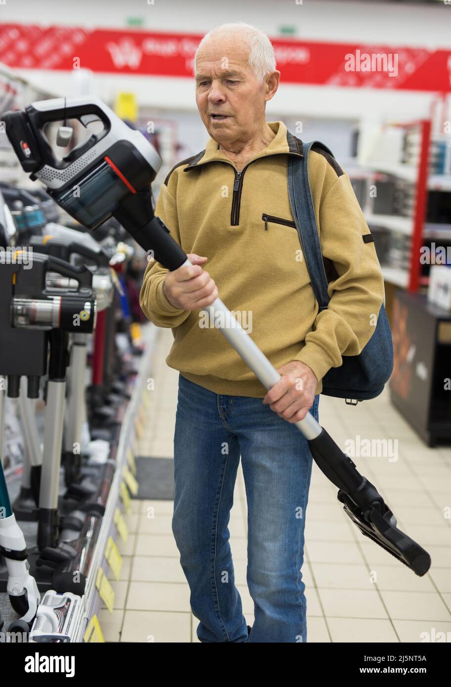 Uomo anziano che sceglie la felpa con cappuccio verticale nello showroom del negozio di elettrodomestici Foto Stock