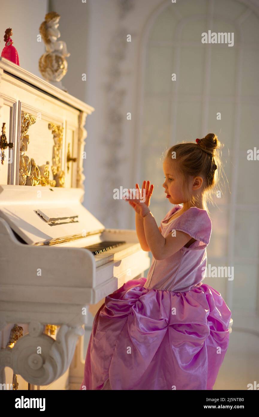 Bella ragazza che gioca piano in un bel vestito Foto Stock