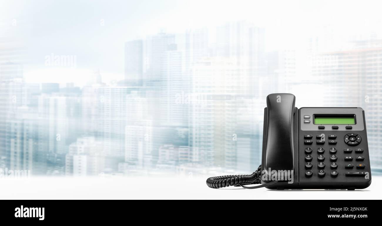telefono con VoIP su tavola bianca su sfondo urbano sfocato. Assistenza clienti, concetto call center. VoIP moderno del telefono. Ufficio Business moderno Foto Stock