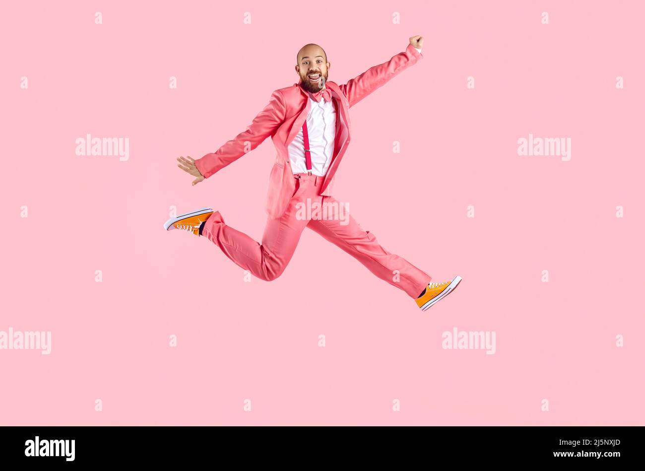 Felice divertente giovane uomo in tuta divertirsi saltando isolato su sfondo rosa pastello. Foto Stock