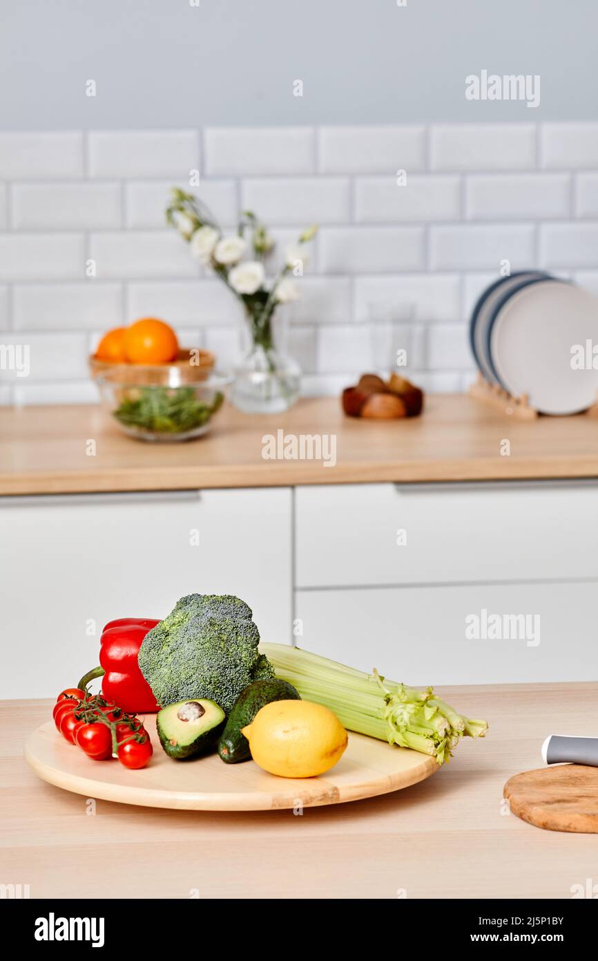 Immagine verticale di verdure fresche su tavola di legno in cucina preparandosi per piatti vegetariani Foto Stock