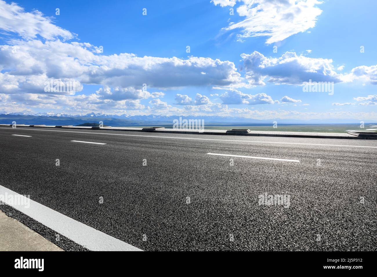 Strada asfaltata vuota sotto il cielo blu. Sfondo stradale e cielo. Foto Stock