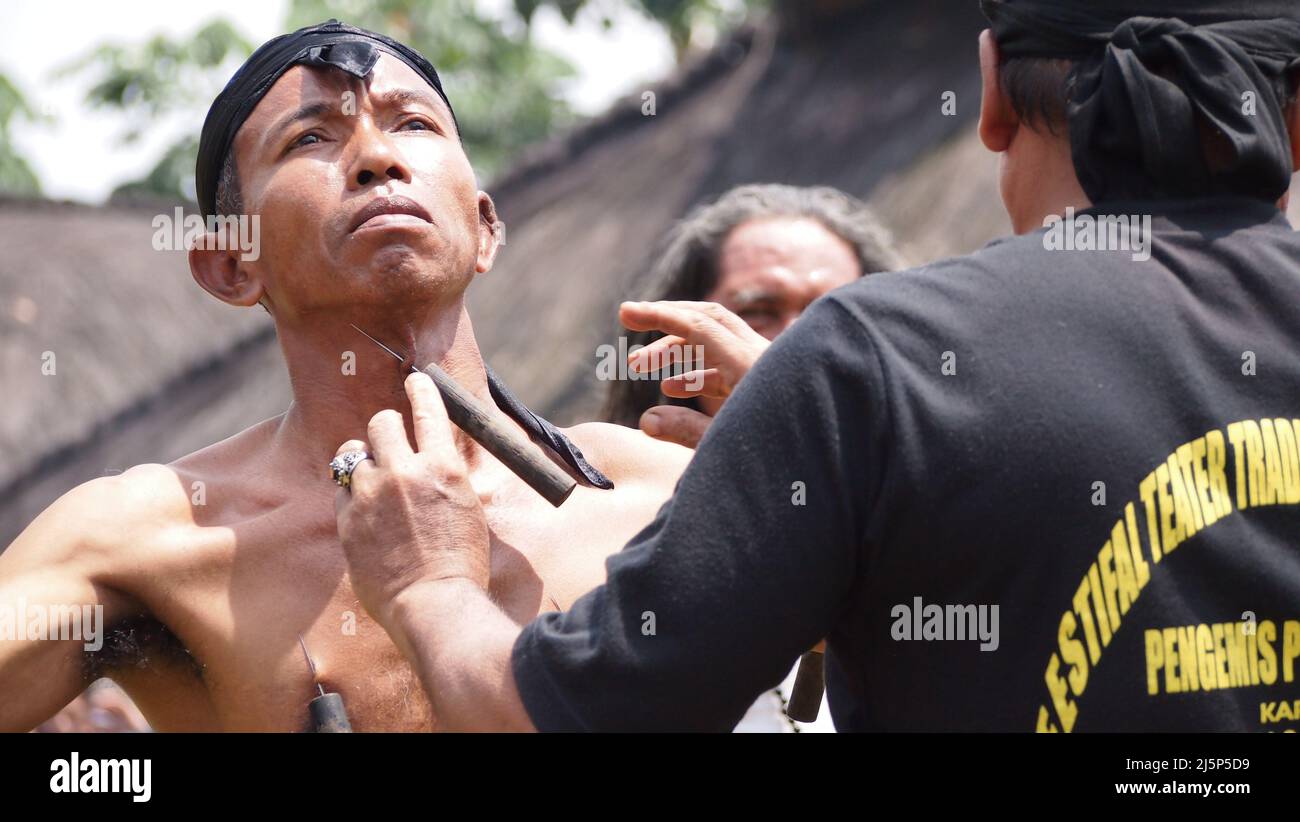 Un uomo mostra fuori l'uomo Magica mostra la magia del suo sistema immunitario da essere pugnalati da diversi oggetti affilati nel collo e corpo in un culturale f Foto Stock
