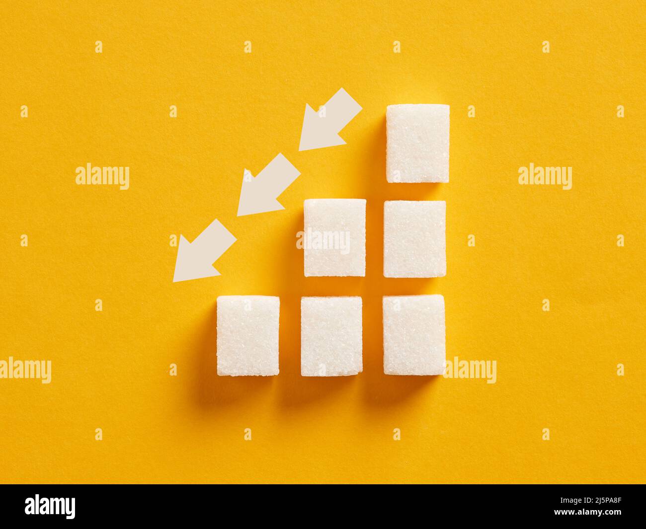 Grafico ascendente a cubetti di zucchero con frecce discendenti che indicano per ridurre l'assunzione di zucchero e la nutrizione sana. Foto Stock