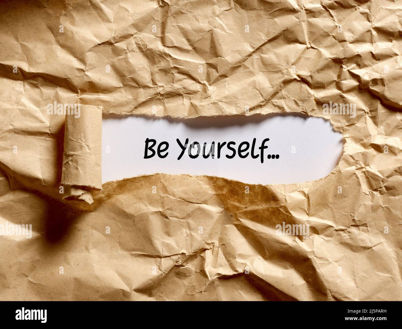 Il messaggio motivazionale sia voi stessi scritto sotto una carta strappata marrone. Foto Stock