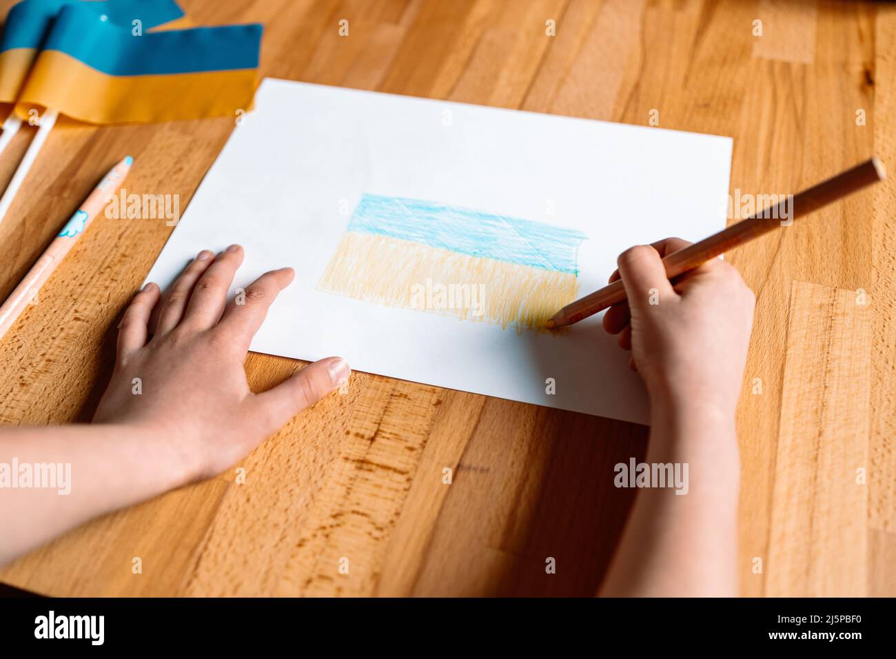 I bambini hanno le mani con matita di colore giallo e blu che disegnano la bandiera Ucraina all'interno della casa Foto Stock