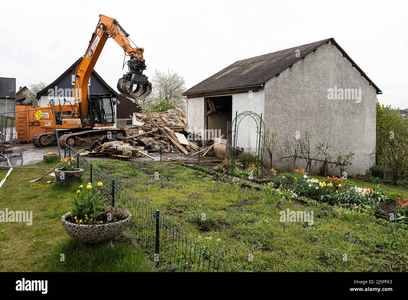 25 aprile 2022, Renania Settentrionale-Vestfalia, Höxter: Un escavatore si trova dietro una recinzione nella cosiddetta "casa dell'orrore" di Höxter. Nelle prime ore del mattino, gli escavatori demolitori hanno demolito l'edificio nel quartiere di Bosseborn. Per anni, diverse donne sono state abusate e torturate da una coppia nella proprietà. Due delle vittime sono morte per le loro gravi lesioni. Foto: Swen Pförtner/dpa Foto Stock