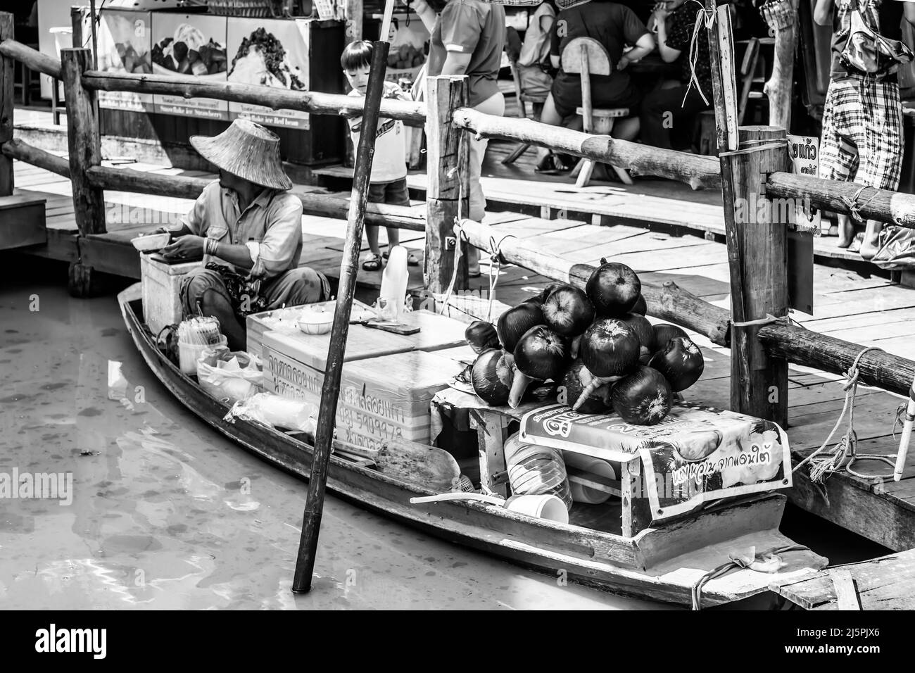 Pattaya, Thailandia - 6 dicembre 2009: Venditore in barca al mercato galleggiante di Pattaya che vende latte di cocco. Fotografia in bianco e nero Foto Stock