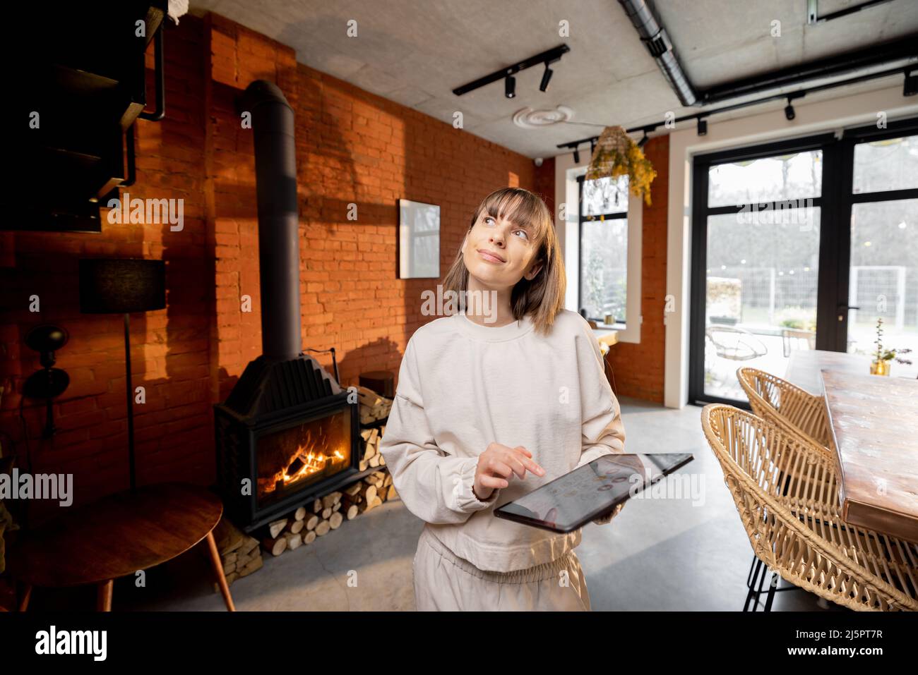 Donna in piedi con un tablet digitale in un accogliente soggiorno in stile loft Foto Stock