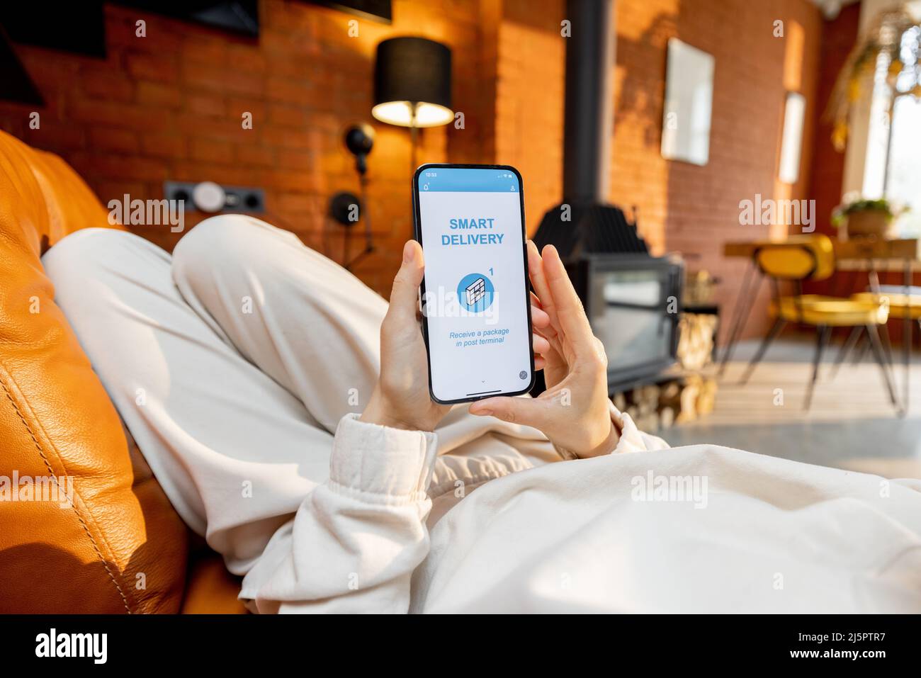 Donna che usa uno smartphone con un'applicazione di consegna in esecuzione a casa Foto Stock