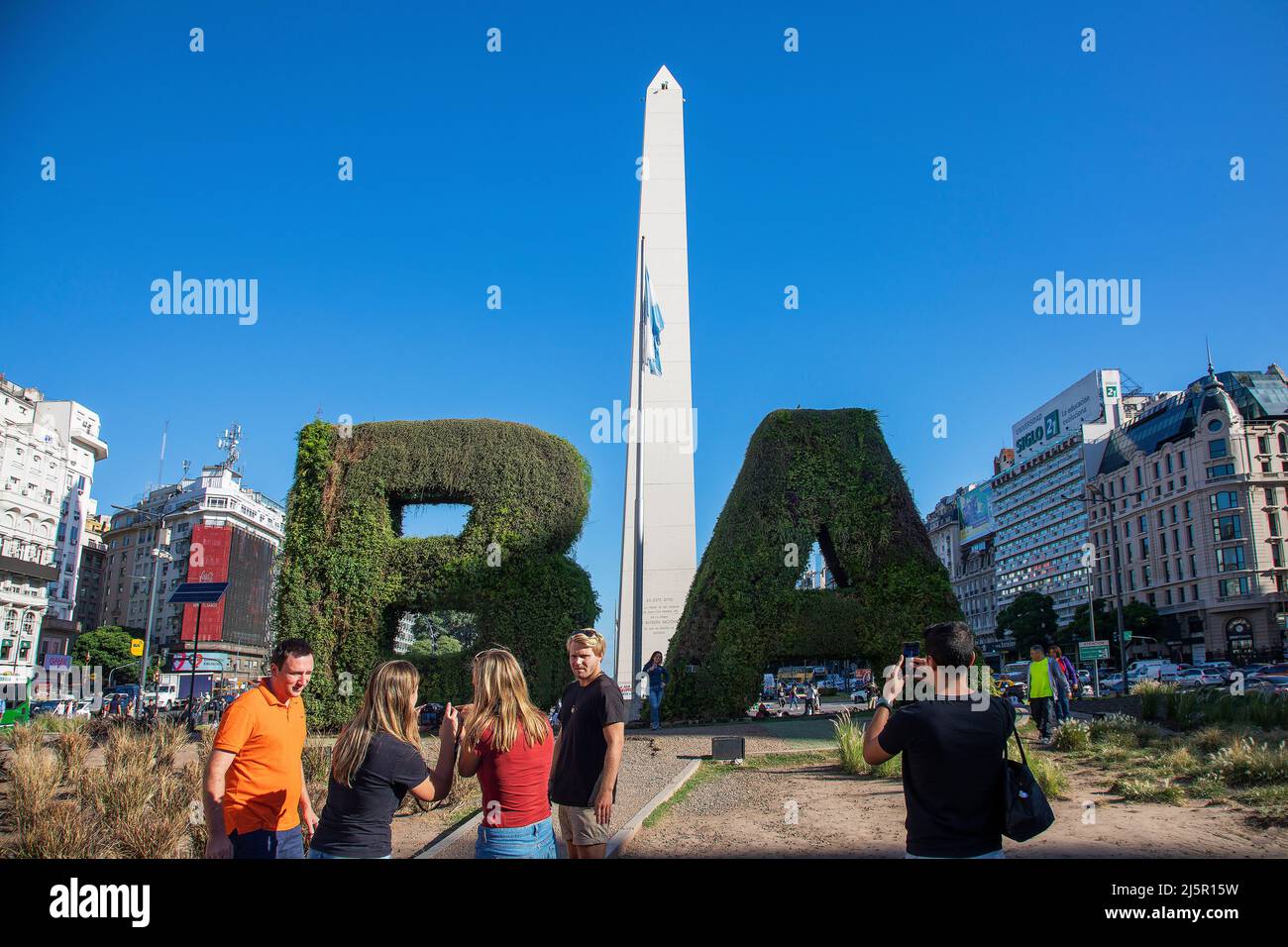 Argentina, Buenos Aires - i turisti di fronte all'obelisco su 9 de Julio Avenue prendono le foto da eachother con le iniziali BA. Foto Stock