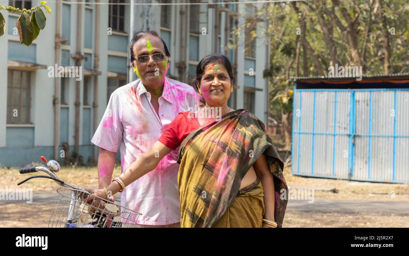 Una coppia indiana senior con volti colorati che giocano holi - il festival dei colori Foto Stock