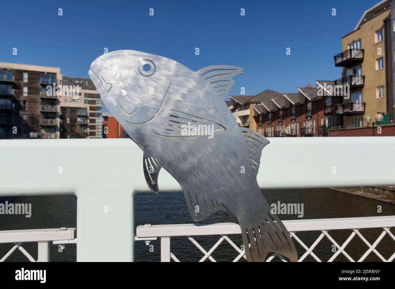 Sculture lucide di pesci metallici su un ponte a Roath Basin, Cardiff Bay. Giorno di sole, primavera 2022. Aprile. Foto Stock