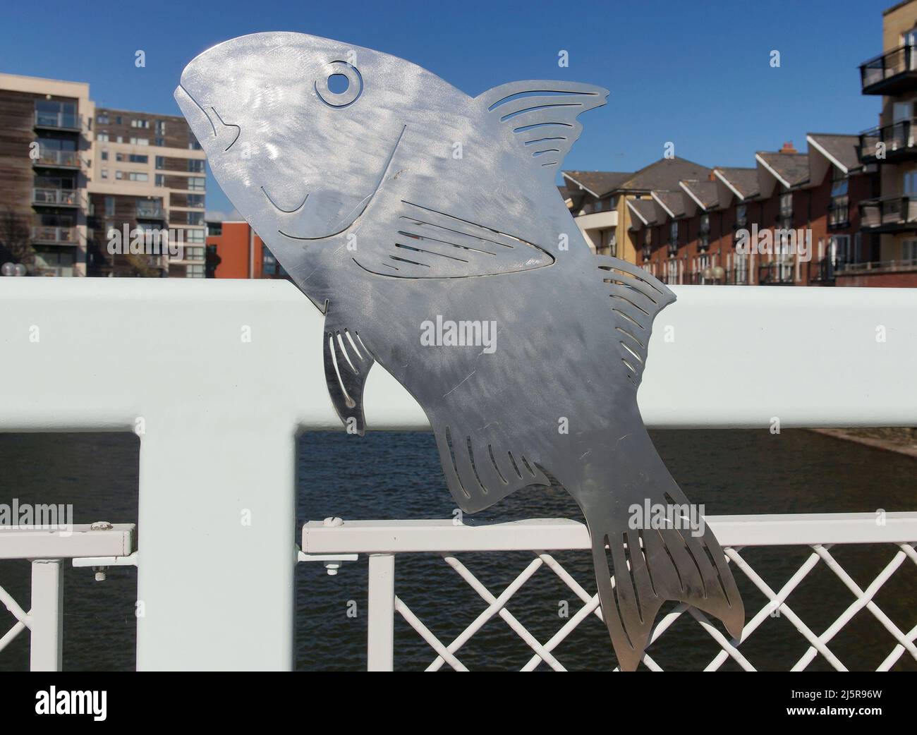 Sculture lucide di pesci metallici su un ponte a Roath Basin, Cardiff Bay. Giorno di sole, primavera 2022. Aprile. Foto Stock