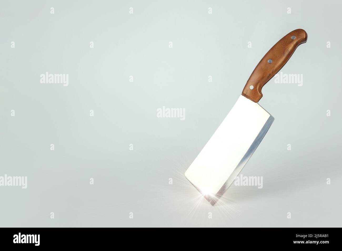 Coltello da cucina equilibrato alla sua fine. Sharp grande coltello da cucina su una superficie gtey con luce solare. Foto Stock