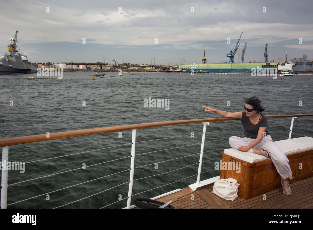 Donna che punta alle navi di South Bay da una crociera turistica Foto Stock