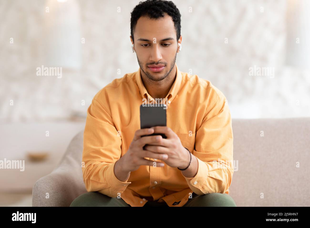 Giovane uomo arabo che usa il cellulare indossando le cuffie Foto Stock