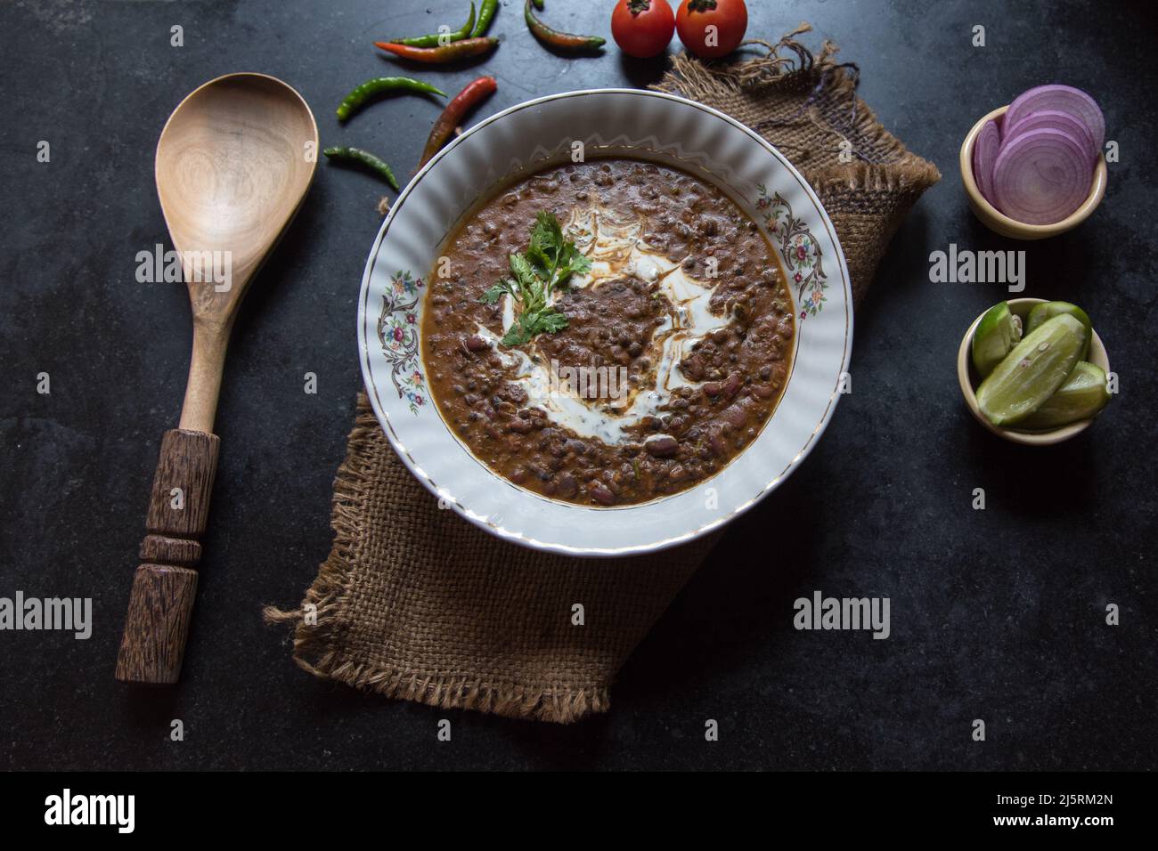 Zuppa dal makhni o lenticchie nere servita in una ciotola insieme ai condimenti. Messa a fuoco selettiva. Foto Stock