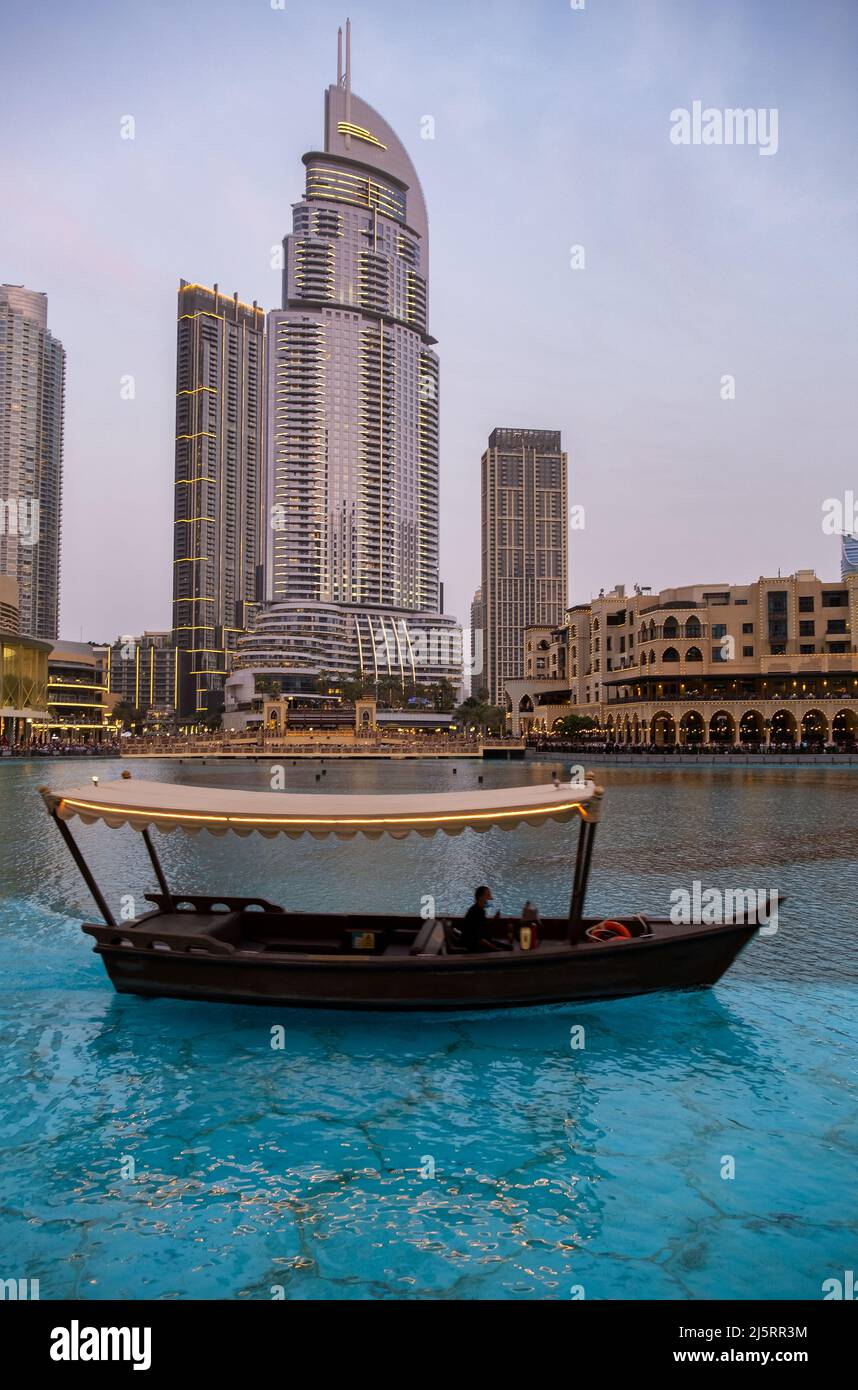 Vista del centro commerciale di Dubai e della Fontana di Dubai catturata in serata con una tipica barca in primo piano. Il Dubai Mall è il più grande centro commerciale della Foto Stock