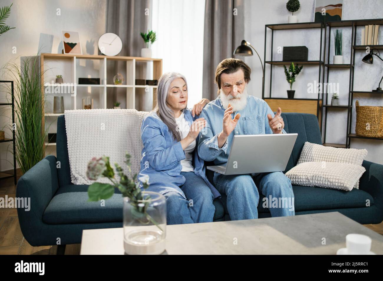 Coppia felice anziana che abbraccia l'uso del notebook insieme. Sorridente famiglia di lettura notizie, shopping online a casa, anziani e computer concetto. Foto Stock