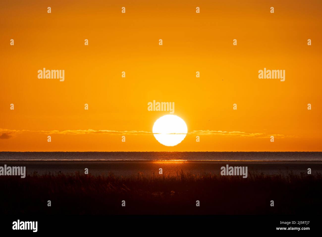 L'inverno sorge in un cielo arancione sul canale inglese con la palude di acqua salata di Pegwell Bay, un'area di protezione speciale, in primo piano. Foto Stock