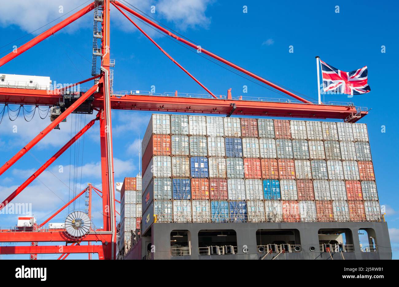 Nave container nel porto con bandiera del Regno Unito sulla gru. Economia del Regno Unito, importazione, esportazione, produzione, posti di lavoro, recessione, inflazione... concetto Foto Stock