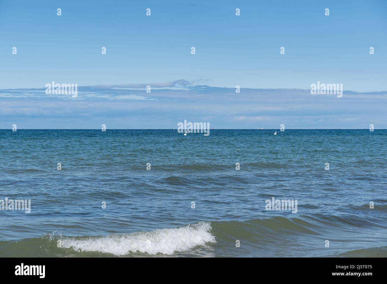 Acqua e onde del Mar Baltico in una splendida giornata estiva. Stagcape di fronte all'orizzonte con boe bianche nell'acqua. Scena idilliaca con pace. Foto Stock