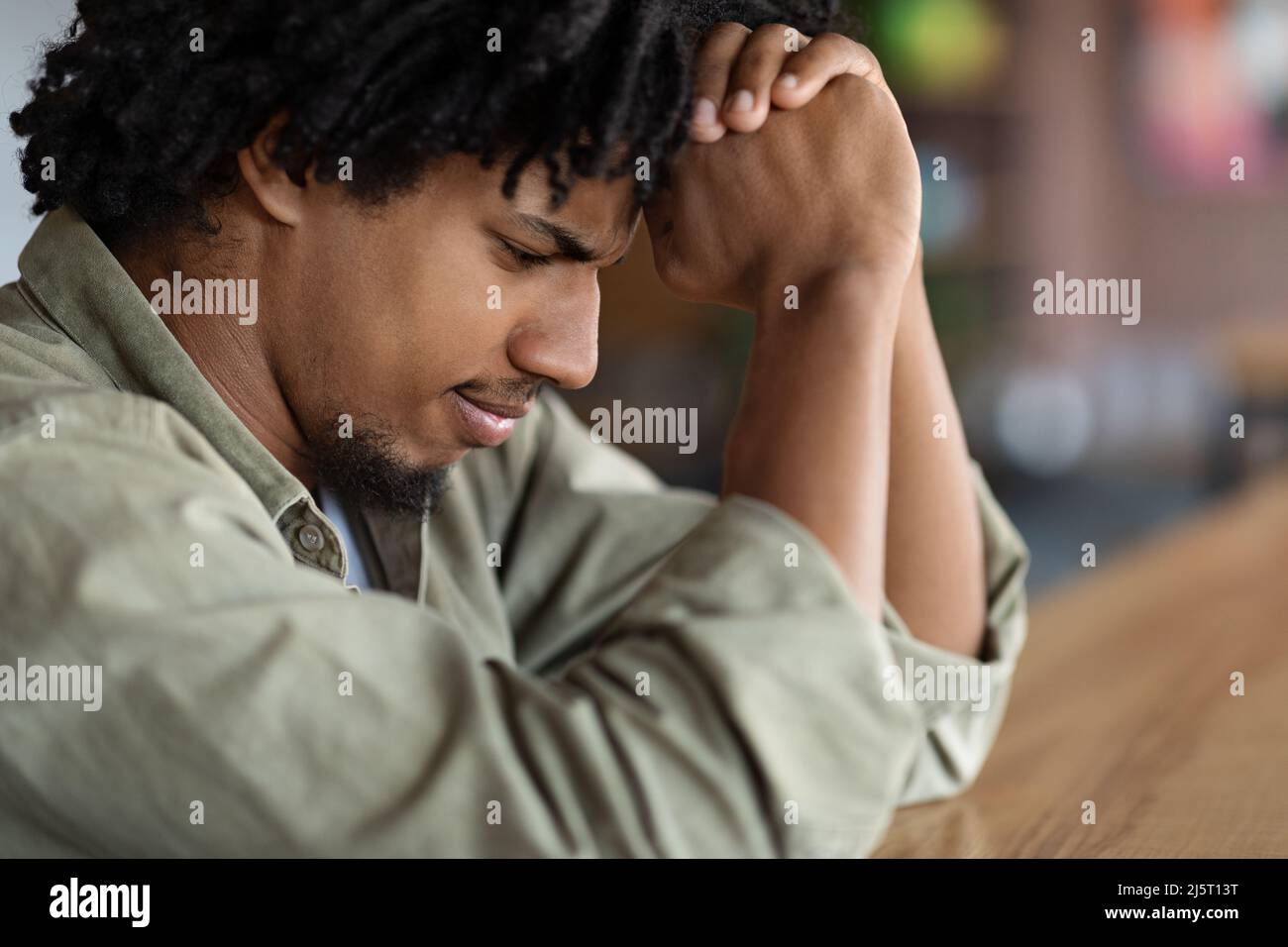 Triste serio concentrato giovane africano americano curly maschio pregare o pensare a risolvere il problema Foto Stock