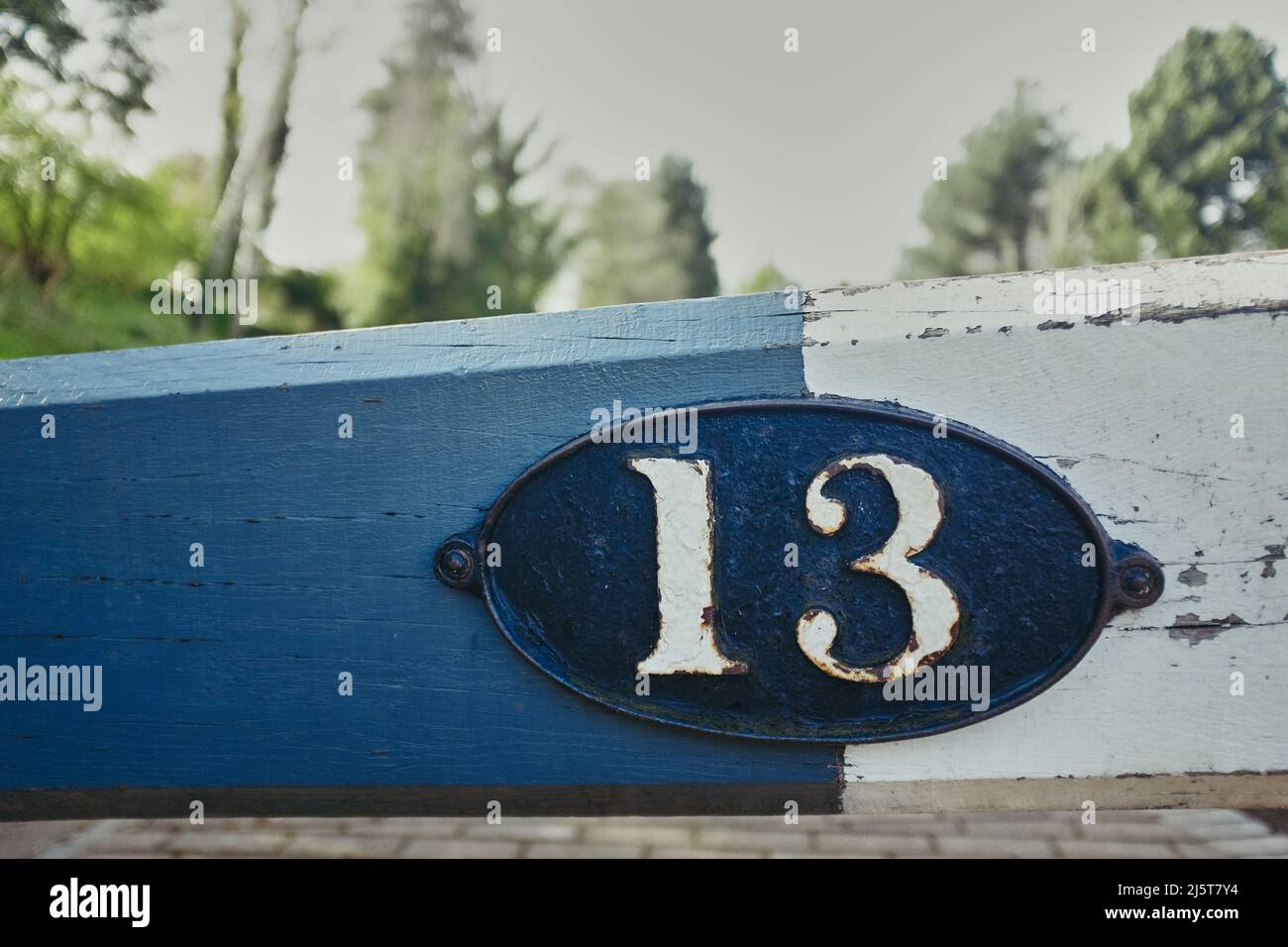 Una vecchia piastra metallica fissata su una trave di legno con i numeri 13 stampigliati su di essa Foto Stock