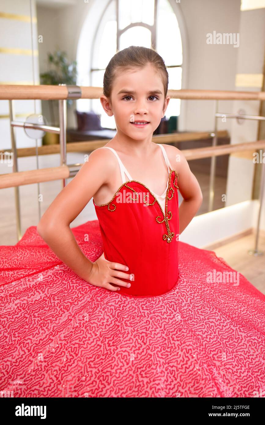 Carino ritratto di una bella ballerina in un abito rosso performance con tutu rosa. Sorride perché è felice di diventare una palla professionale Foto Stock