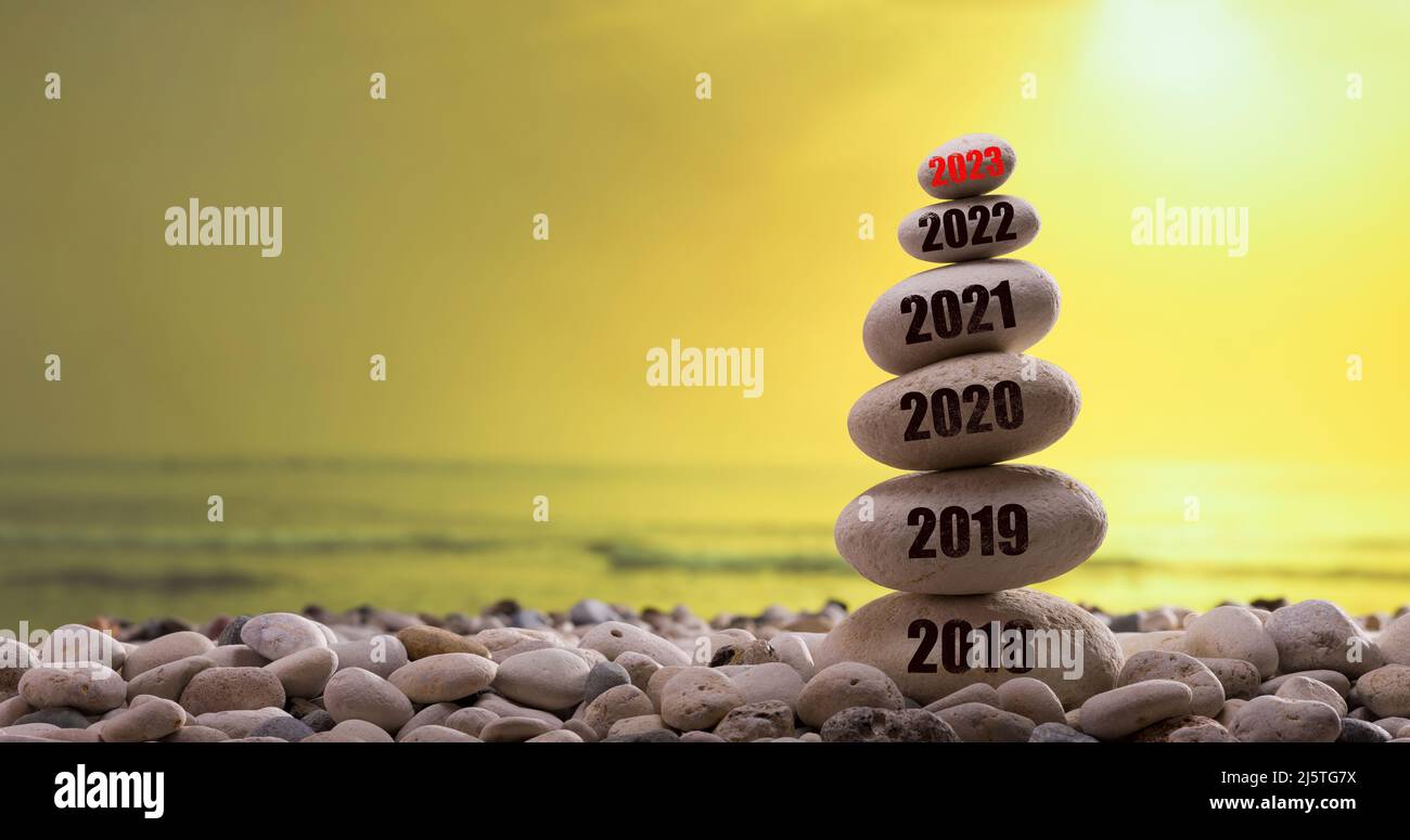 il nuovo anno 2023 sarà presto disponibile. Inizio anno nuovo 2023. Anni scritti sulla torre di pietra. Dati dell'anno dal 2018 al 2023. Tramonto sullo sfondo Foto Stock