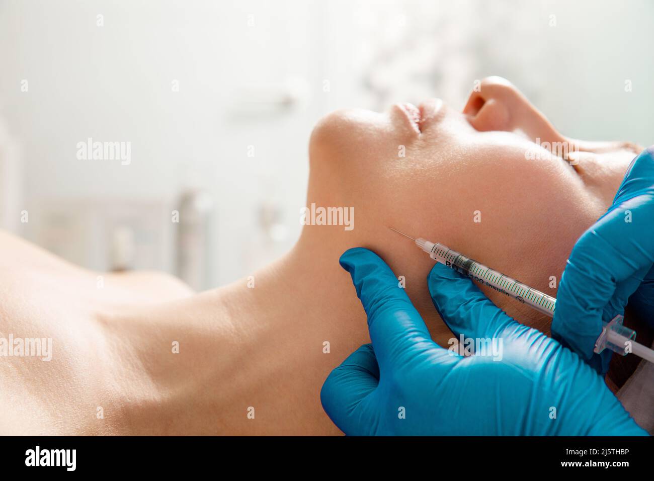Il cosmetologo esegue la procedura di sollevamento del mento iniettando le iniezioni di bellezza. Medico iniettando acido ialuronico nel ching di una donna come un viso Foto Stock