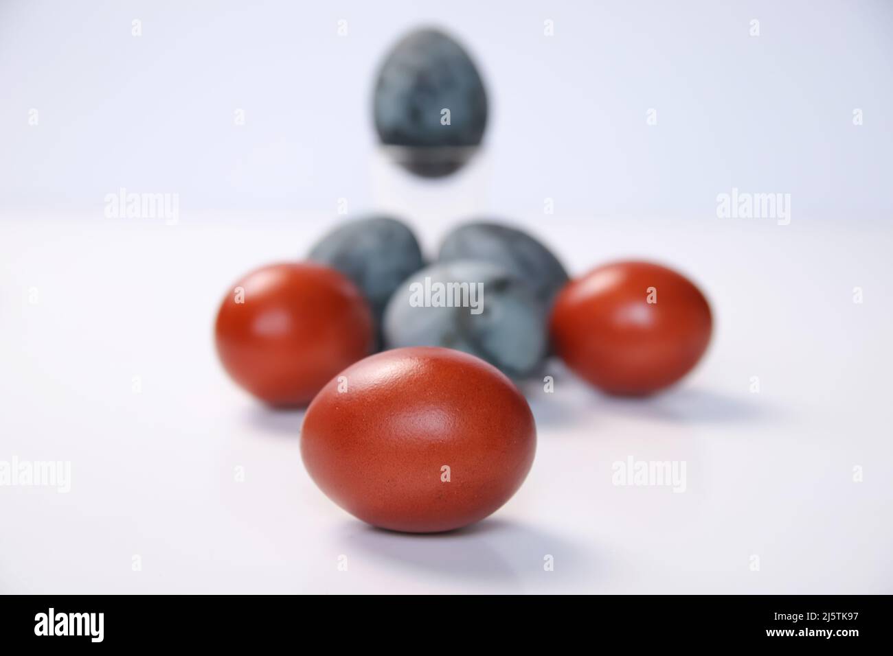 Defocalizzare le uova blu e rosse su sfondo bianco. Concetto minimo di festa di Pasqua. Design, arte visiva, minimalismo. Concetto di equilibrio e armonia. Mentale Foto Stock