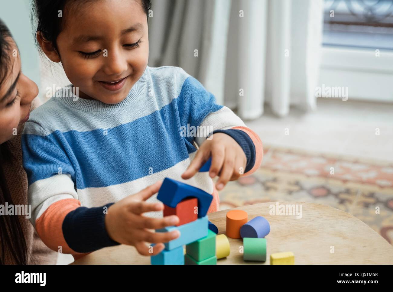 Madre e figlio latinoamericani che si divertono a giocare con i blocchi di giocattoli in legno a casa - Family Time Together Foto Stock