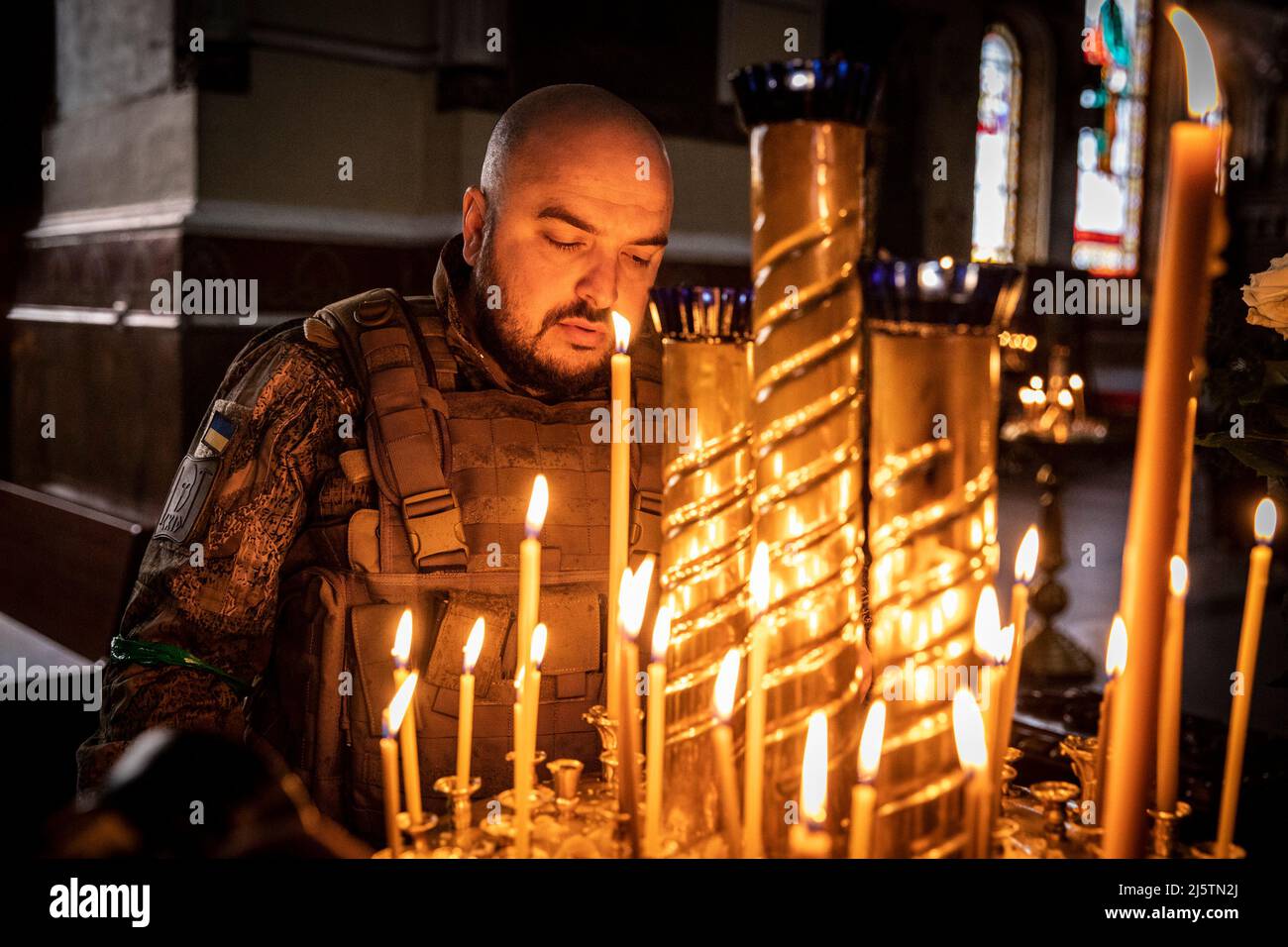 Kharkiv, Ucraina. 24th Apr 2022. Roman (33), soldato dei servizi militari ucraini che illuminano le candele in un monastero ortodosso a Kharkiv. Le celebrazioni pasquali ortodosse vengono quando la guerra Ucraina-Russia è durata per due mesi dall'inizio dell'invasione russa del febbraio 24, gli ucraini ora pregavano per la pace e cordoglio a coloro che sono scomparsi dalla guerra, che ha ucciso numerosi civili e soldati. Credit: SOPA Images Limited/Alamy Live News Foto Stock