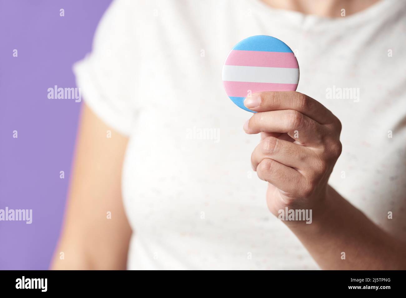 Persona non riconoscibile che tiene in mano un badge o un pin della bandiera della trasmissione. Concetti di orgoglio di identità, diversità di genere, uguaglianza e non discriminazione. Foto Stock