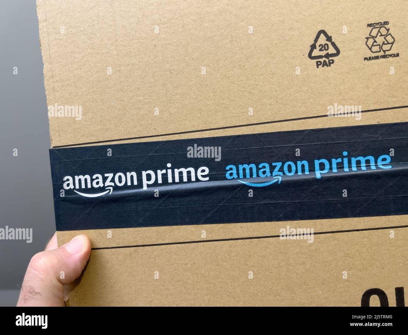 Parigi, Francia - Apr 25, 2022: Primo piano POV maschio tenuta a mano nuovo pacchetto corrugato ecologico con logo Amazon prime online shopping e commercio Foto Stock