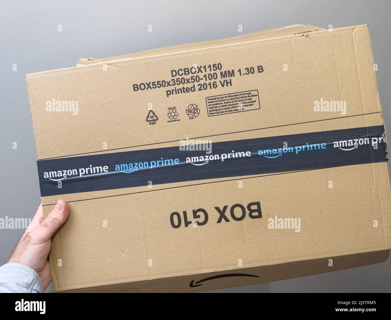 Parigi, Francia - Apr 25, 2022: Mano maschio POV con nuovo pacchetto corrugato ecologico con logo Amazon prime online shopping e commerce Foto Stock