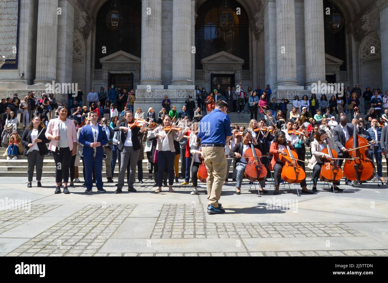 Le persone suonano strumenti musicali di fronte alla Mid-Manhattan Library di New York il 24 aprile 2022. Foto Stock