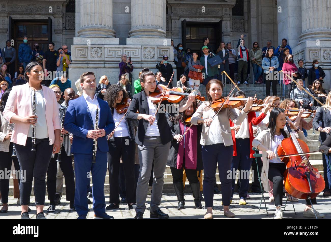 Le persone suonano strumenti musicali di fronte alla Mid-Manhattan Library di New York il 24 aprile 2022. Foto Stock