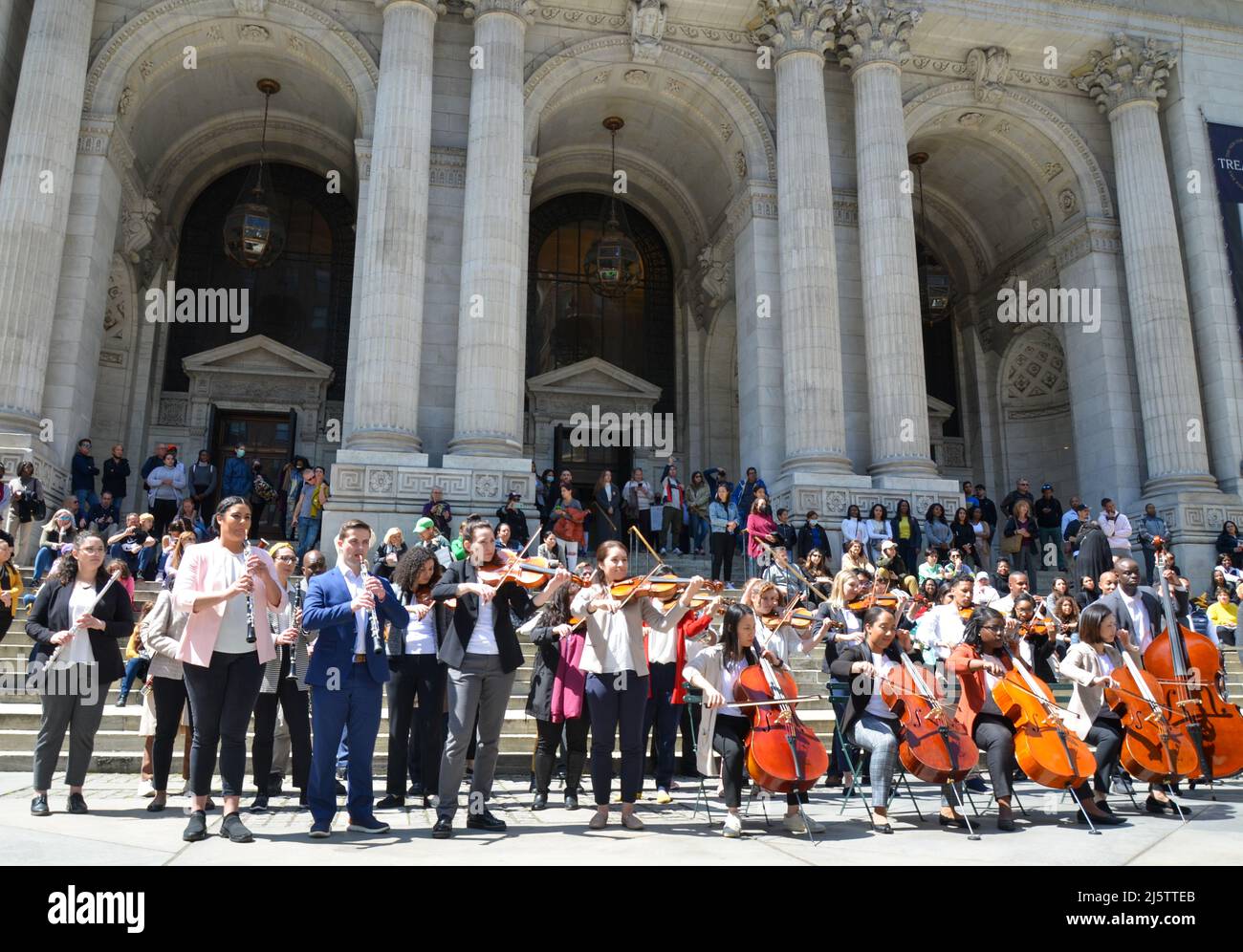 Le persone suonano strumenti musicali di fronte alla Mid-Manhattan Library di New York il 24 aprile 2022. Foto Stock