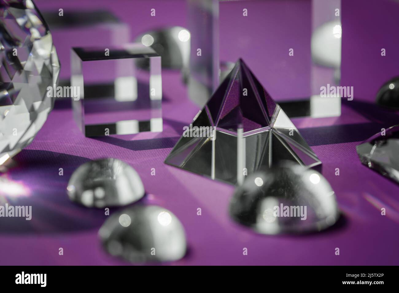Luce rifrangente a prisma di cristallo, cristalli magici e piramide, sfera e cubo su sfondo viola. Pratica di cristallo di guarigione spirituale. Feng Shui, bravo Foto Stock