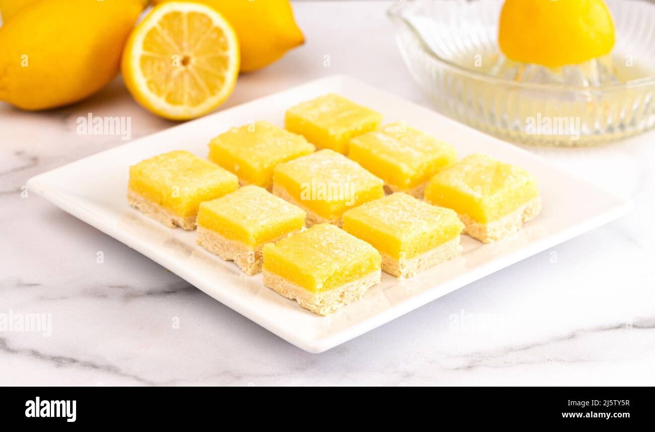 Un lotto di limoni su un piatto quadrato sul banco della cucina Foto Stock