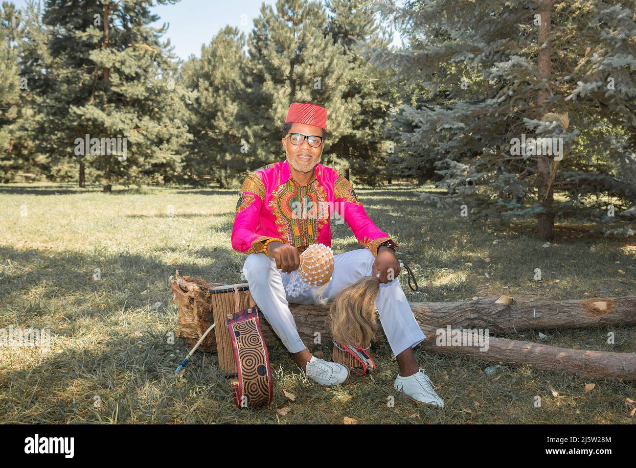 Bell'uomo africano in costume nazionale suona un tamburo etnico, djembe. Foto Stock