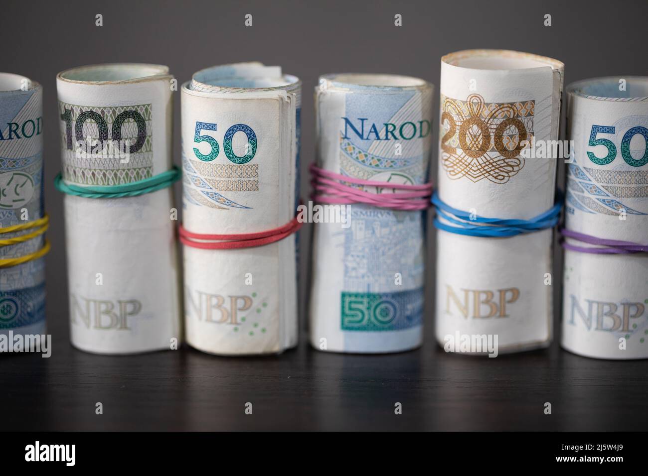 Sul tavolo sono presenti banconote polacche arrotolate in fila e legate con un nastro di gomma. Foto Stock