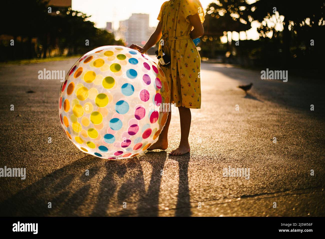 La ragazza si alza in luce dorata con la sfera dell'arcobaleno in abito giallo Foto Stock