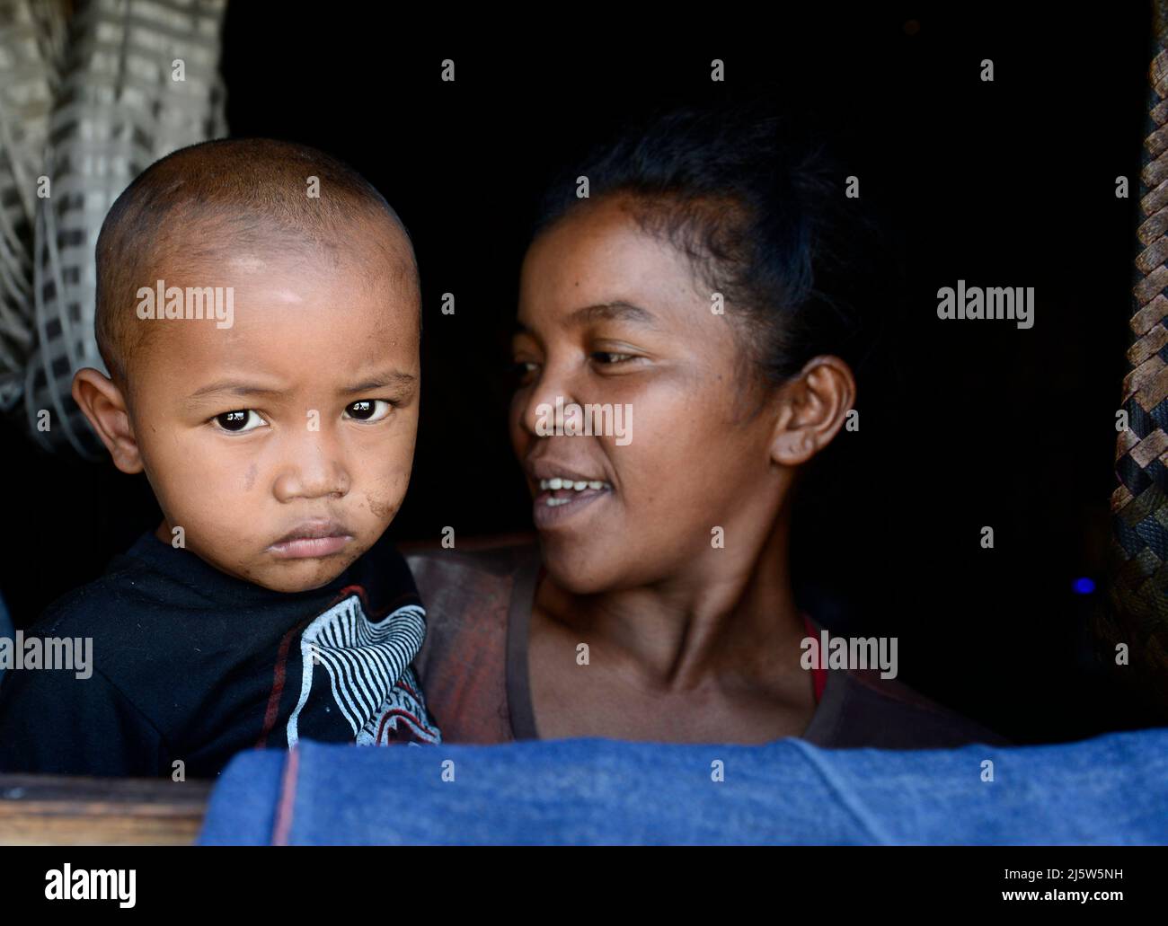 Una famiglia malgascia che guarda fuori la loro finestra di casa. Regione di Ambohimanga, Madagascar. Foto Stock