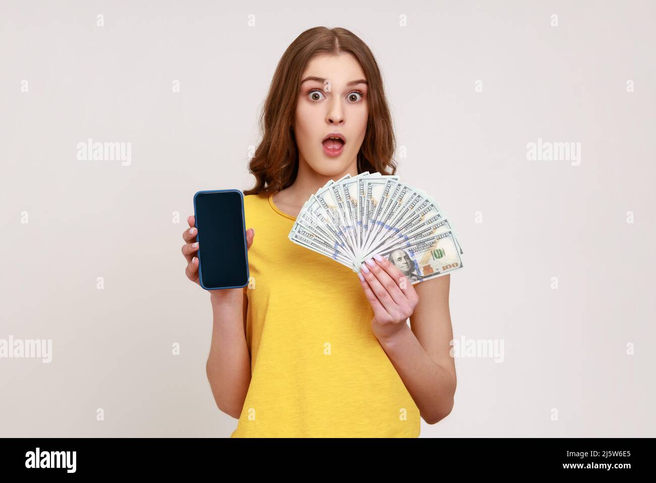 Tenendo smartphone soldi sfondo giallo immagini e fotografie stock ad alta  risoluzione - Alamy