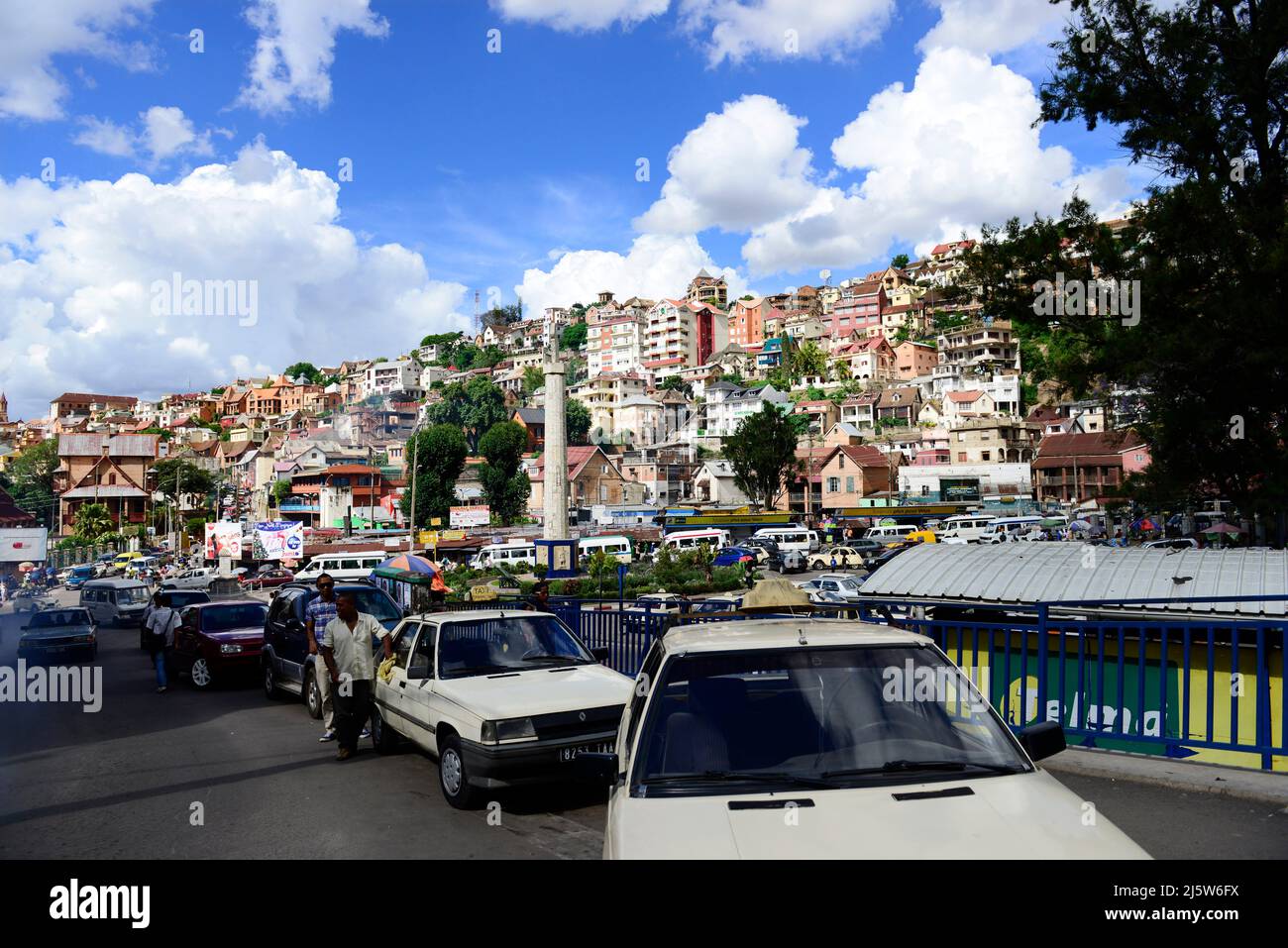 Automobili e persone in piazza MDRM - il pilastro in pietra con una mappa Madagascar segna la rivolta del 1947. Antananarivo, Madagascar. Foto Stock